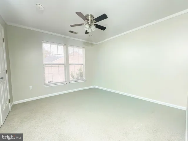 an empty room with ceiling fan and windows