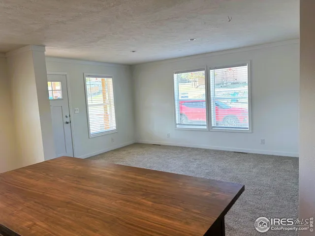 a view of an empty room with wooden floor and windows