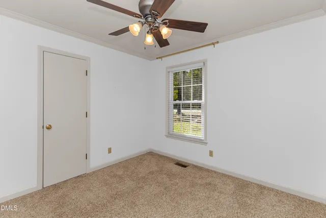 an empty room with window and ceiling fan