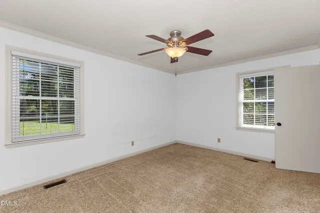an empty room with ceiling fan and window