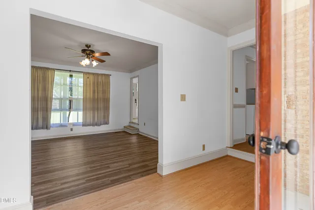 a view of an empty room with a window and wooden floor