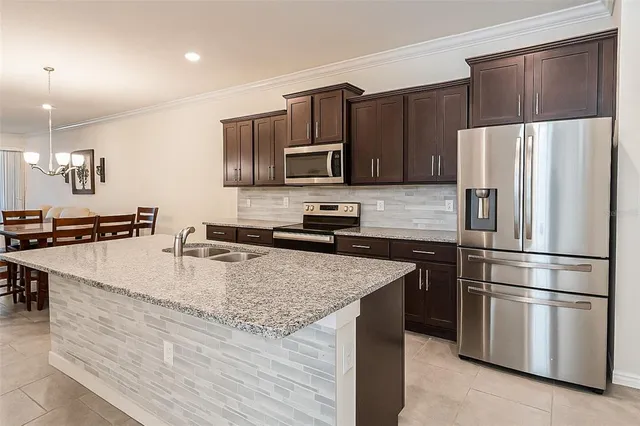 a kitchen with stainless steel appliances granite countertop a refrigerator a stove a sink and a microwave