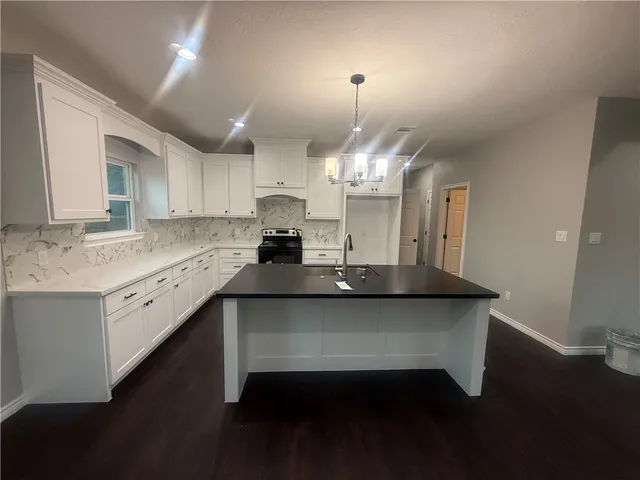 a kitchen with stainless steel appliances a sink dishwasher a stove a dining table and chairs with wooden floor