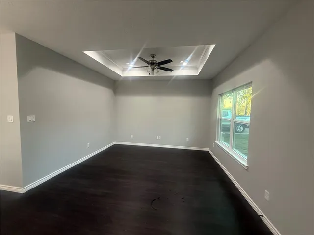 an empty room with wooden floor chandelier fan and windows
