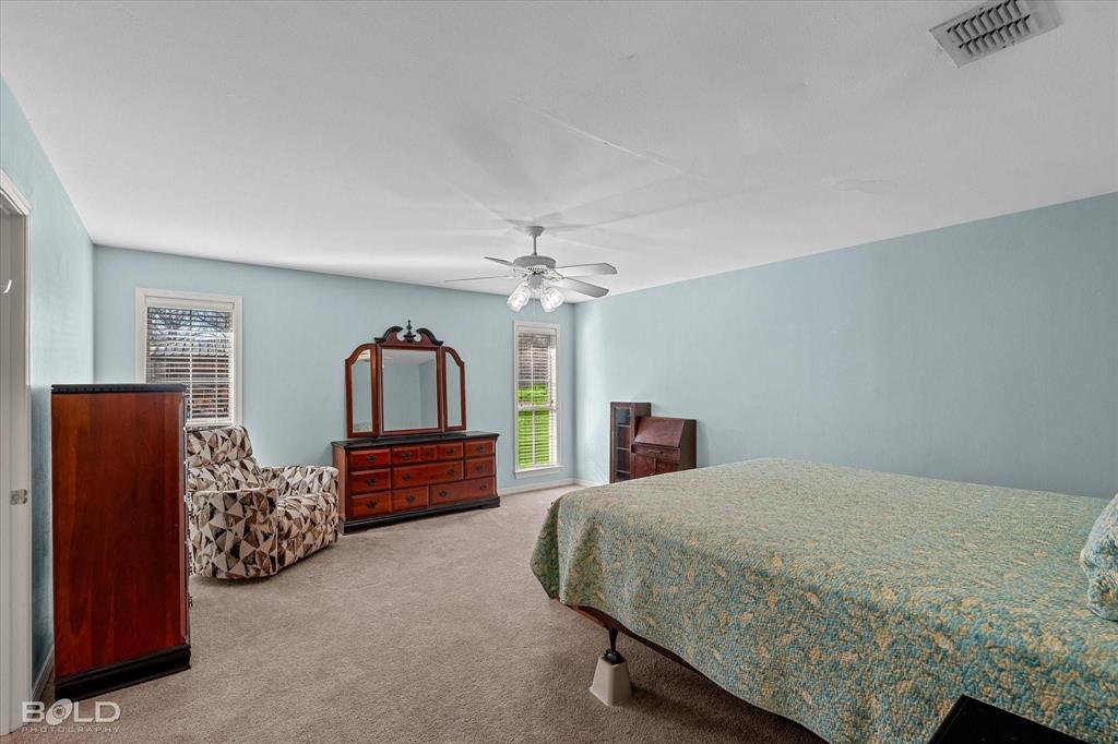 136 Scarborough Road Benton, LA 71006 - Photo 17 of 37 Spacious room featuring light blue walls, neutral carpet, a ceiling fan with light fixture, and multiple windows with horizontal blinds