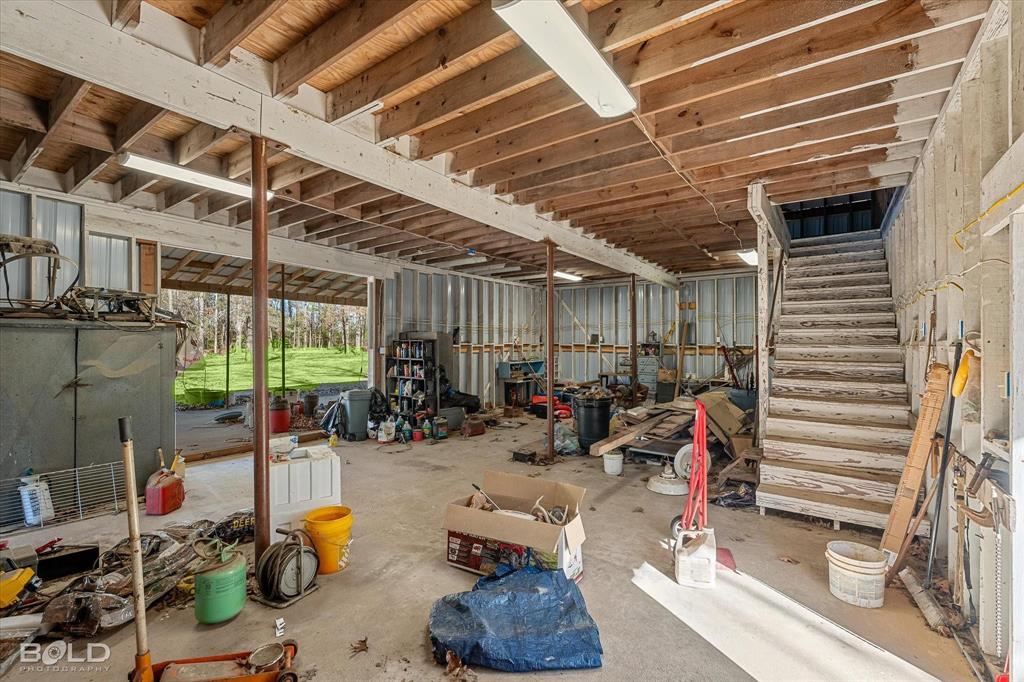 136 Scarborough Road Benton, LA 71006 - Photo 27 of 37 Open-concept lower level with exposed wood beam ceiling, concrete flooring, support columns, and visible wooden staircase