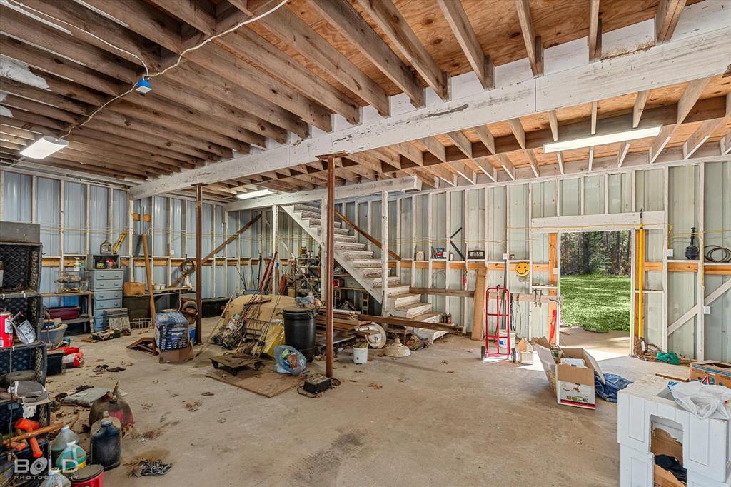 136 Scarborough Road Benton, LA 71006 - Photo 28 of 37 Spacious unfinished interior with exposed wooden joists, concrete flooring, and an open doorway providing direct exterior access