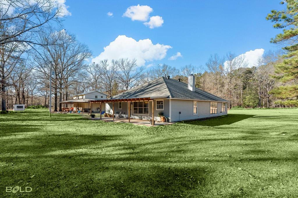 136 Scarborough Road Benton, LA 71006 - Photo 31 of 37 Expansive green lawn surrounding a light-colored siding residence with a hip roof and chimney