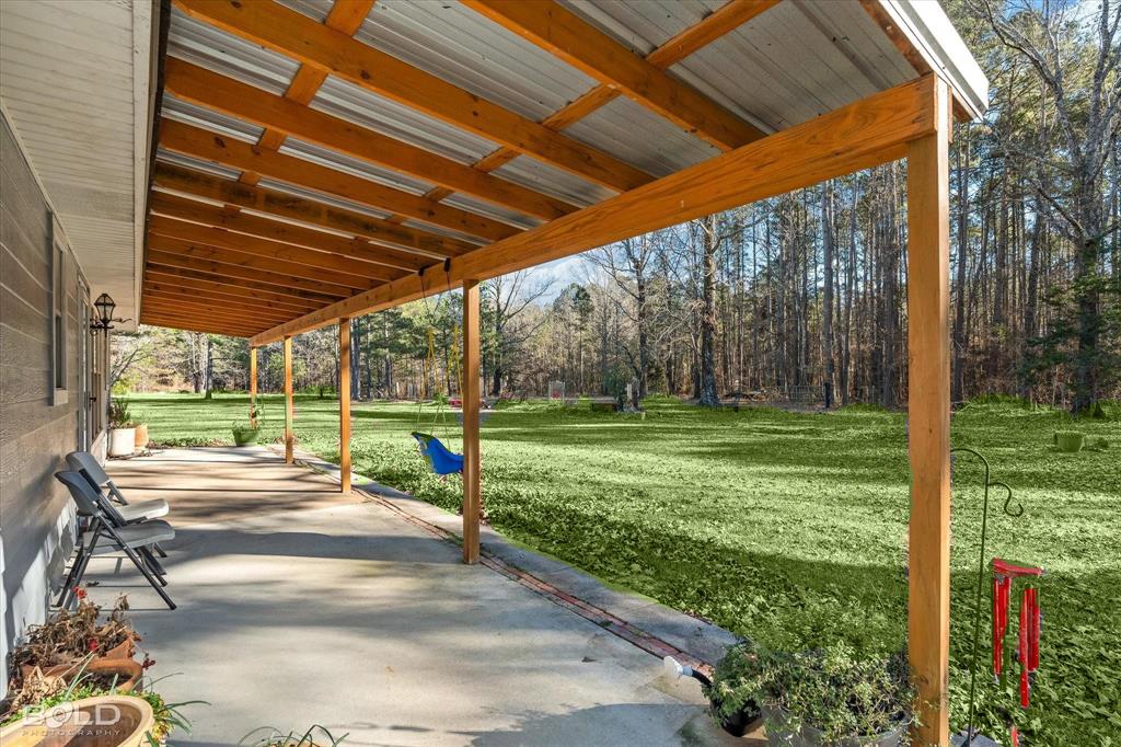 136 Scarborough Road Benton, LA 71006 - Photo 5 of 37 Expansive covered concrete patio featuring a wood-beam ceiling with a corrugated metal roof