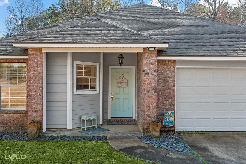 136 Scarborough Road Benton, LA 71006 - Photo 6 of 37 Exterior featuring brick accents, horizontal siding, a light blue entry door, and an attached garage with a panel door