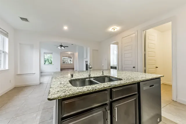 a kitchen with granite countertop kitchen island a sink stainless steel appliances and a window