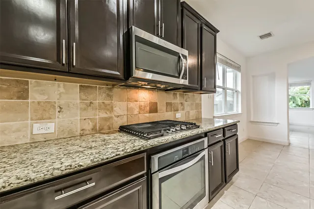 a kitchen with granite countertop cabinets stove top oven and microwave