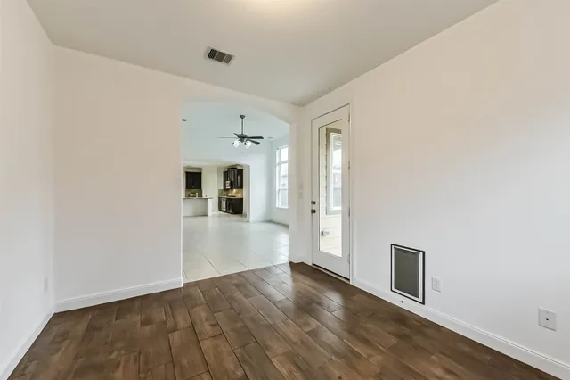 a view of a hallway with wooden floor and a bathroom