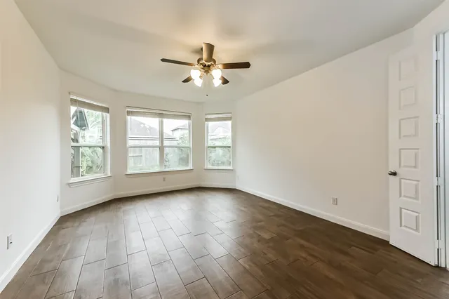a view of an empty room with a window and wooden floor