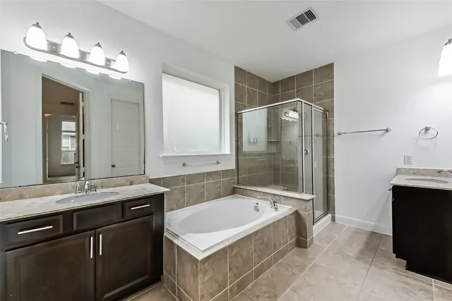 a bathroom with a bathtub a double vanity sink and mirror