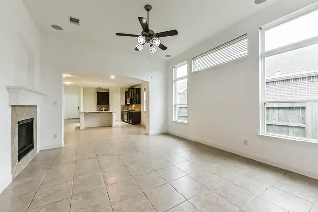 a view of an empty room with a window and kitchen view