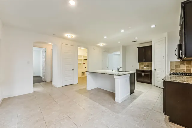 a view of a kitchen with kitchen island granite countertop a refrigerator and a stove top oven