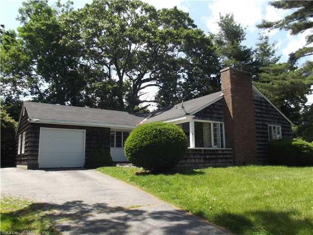 a view of a house with a yard plants and large tree