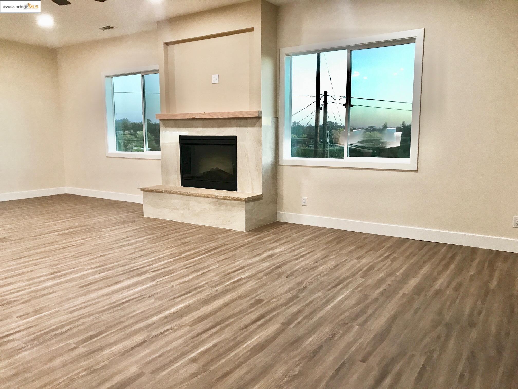 17500 Harvard Mine Road Jamestown, CA 95327 - Photo 14 of 28 Unfurnished living room featuring wood finished floors, a fireplace, a ceiling fan, and recessed lighting