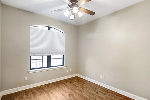 a view of an empty room with window and chandelier fan
