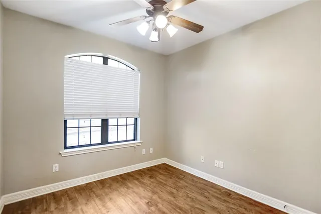 a view of an empty room with window and chandelier fan