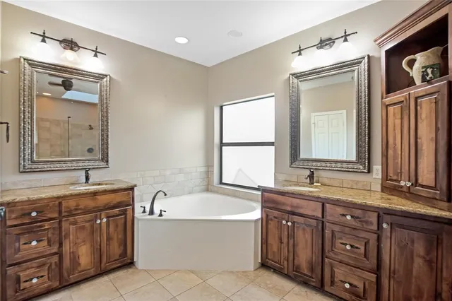 a bathroom with a granite countertop double vanity sink a mirror and a bathtub