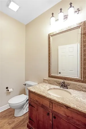a bathroom with a granite countertop sink toilet and mirror