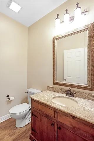 a bathroom with a granite countertop sink toilet and mirror