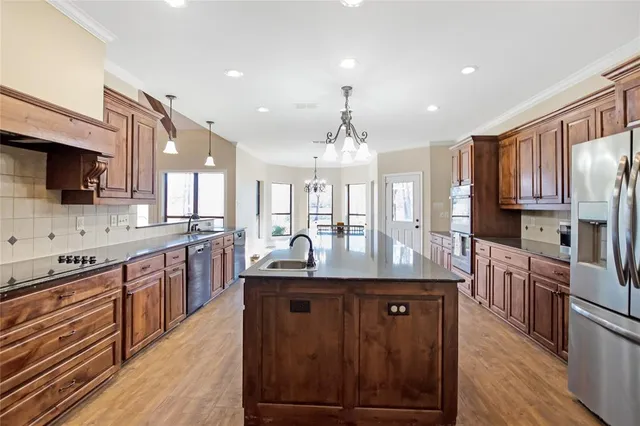 a kitchen with stainless steel appliances granite countertop a sink a stove and a wooden floors