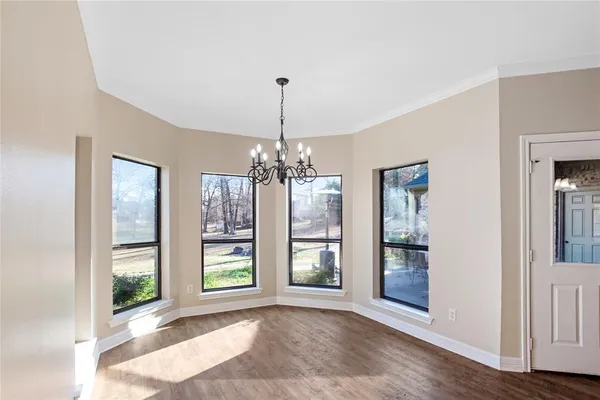 a view of an empty room with window and kitchen view