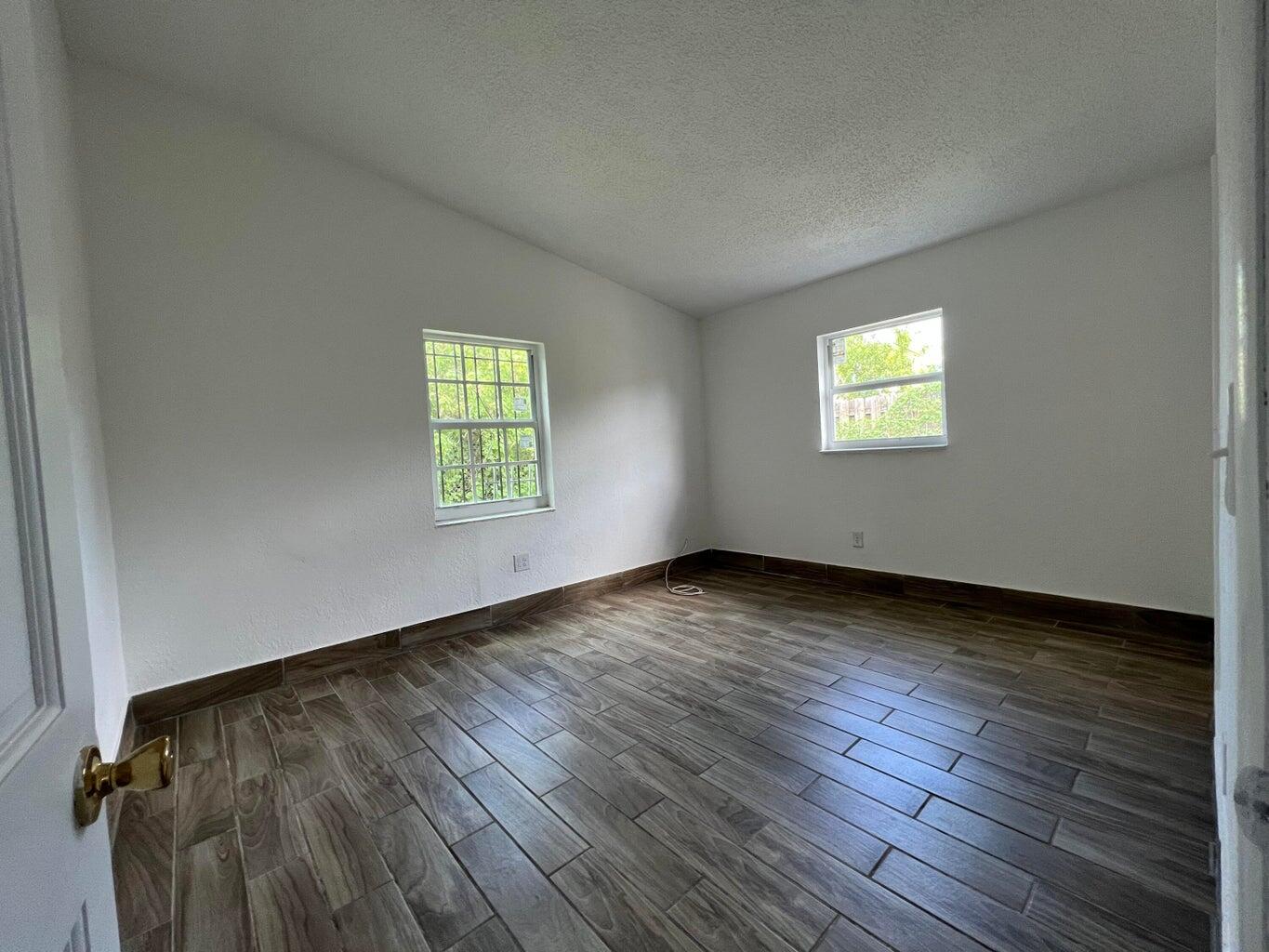 1050 West 7th Street Riviera Beach, FL 33404 - Photo 12 of 15 an empty room with wooden floor and windows