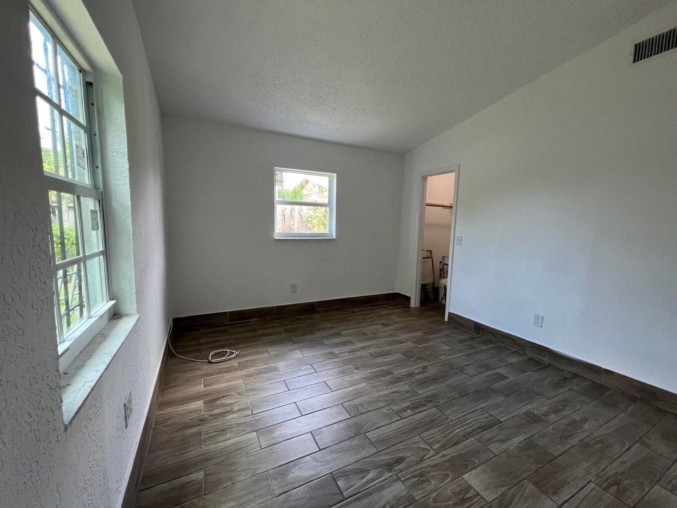 1050 West 7th Street Riviera Beach, FL 33404 - Photo 13 of 15 a view of an empty room with wooden floor and a window