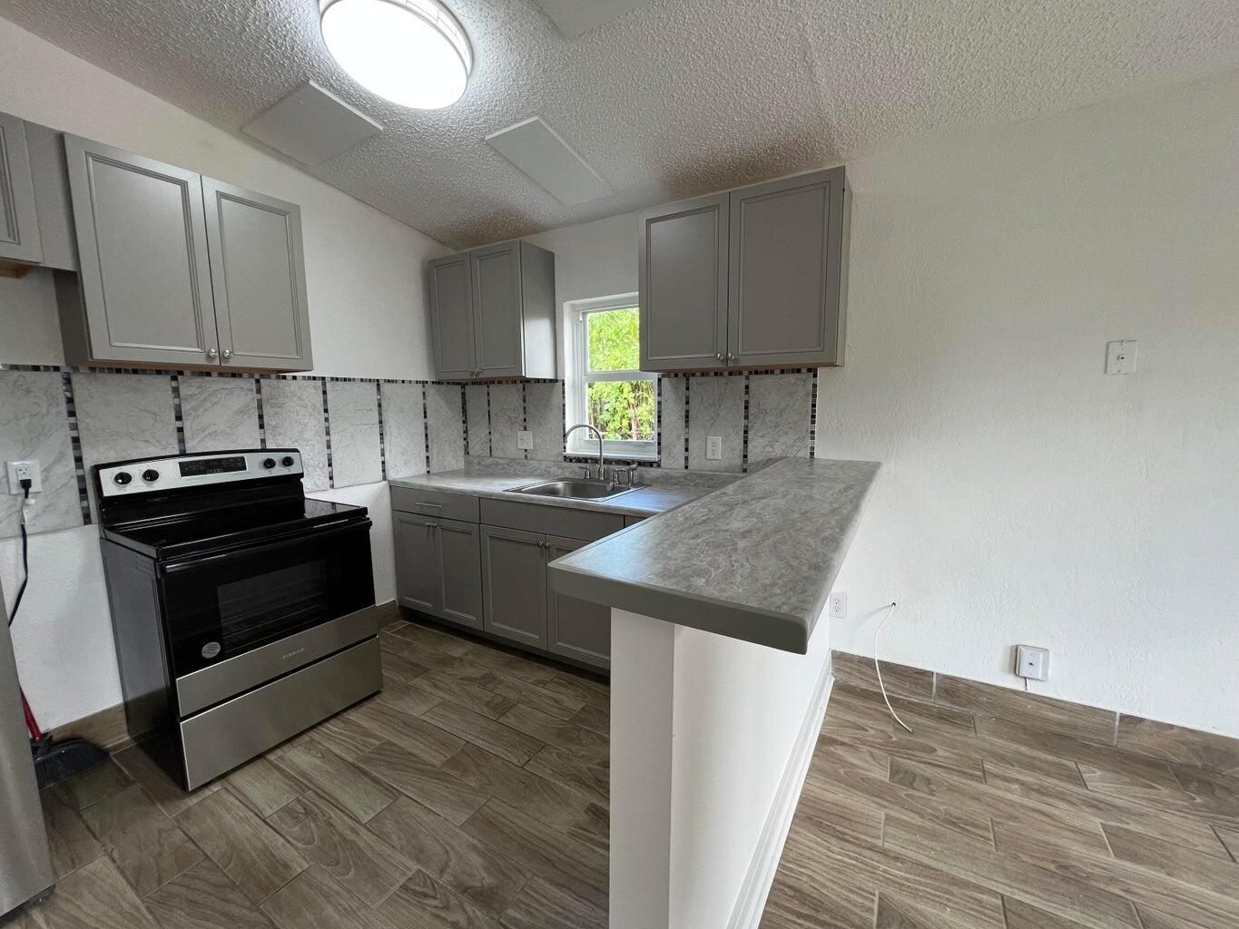 1050 West 7th Street Riviera Beach, FL 33404 - Photo 14 of 15 a kitchen with a sink and a stove top oven