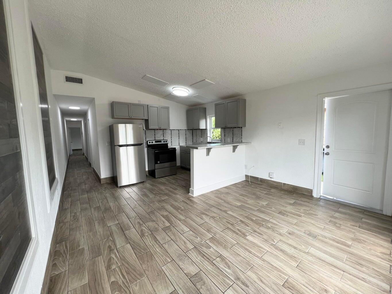 1050 West 7th Street Riviera Beach, FL 33404 - Photo 3 of 15 a view of empty room with wooden floor and window