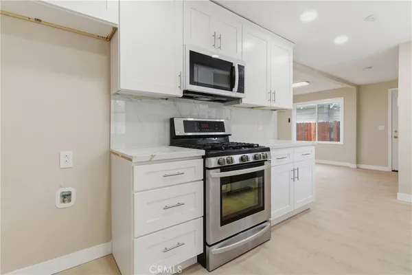 a kitchen with stainless steel appliances granite countertop grey cabinets a stove top oven a sink and dishwasher