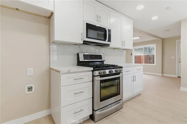 a kitchen with stainless steel appliances granite countertop grey cabinets a stove top oven a sink and dishwasher