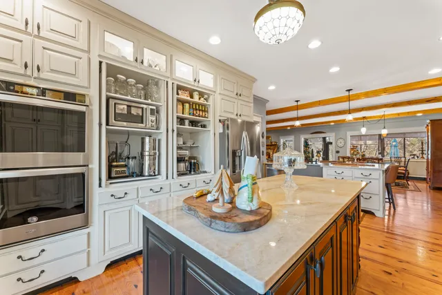 a dining hall view with a large dining table and chairs with the view of kitchen