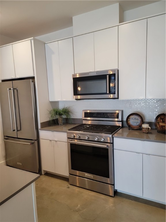 a kitchen with stainless steel appliances white cabinets white stove a microwave and a refrigerator