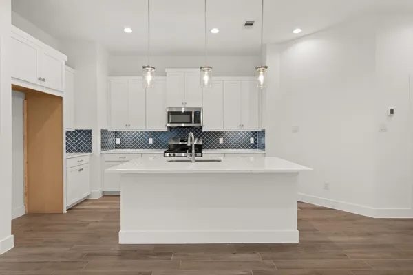 a view of kitchen with stainless steel appliances granite countertop a sink a stove and a refrigerator