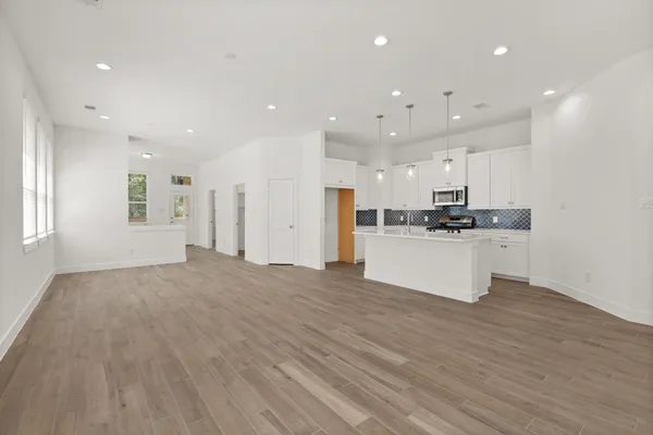 a view of kitchen with kitchen island a sink wooden floor and a refrigerator