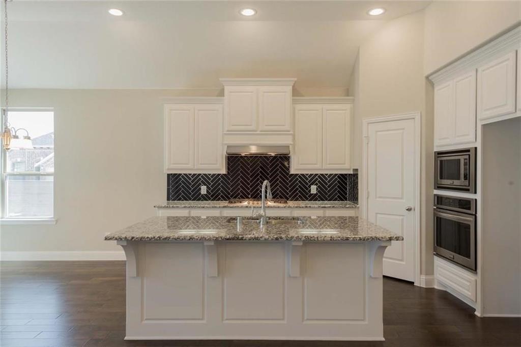 867 Forest Street Little Elm, TX 76227 - Photo 8 of 22 a close view of kitchen island with granite countertop white cabinets and stainless steel appliances