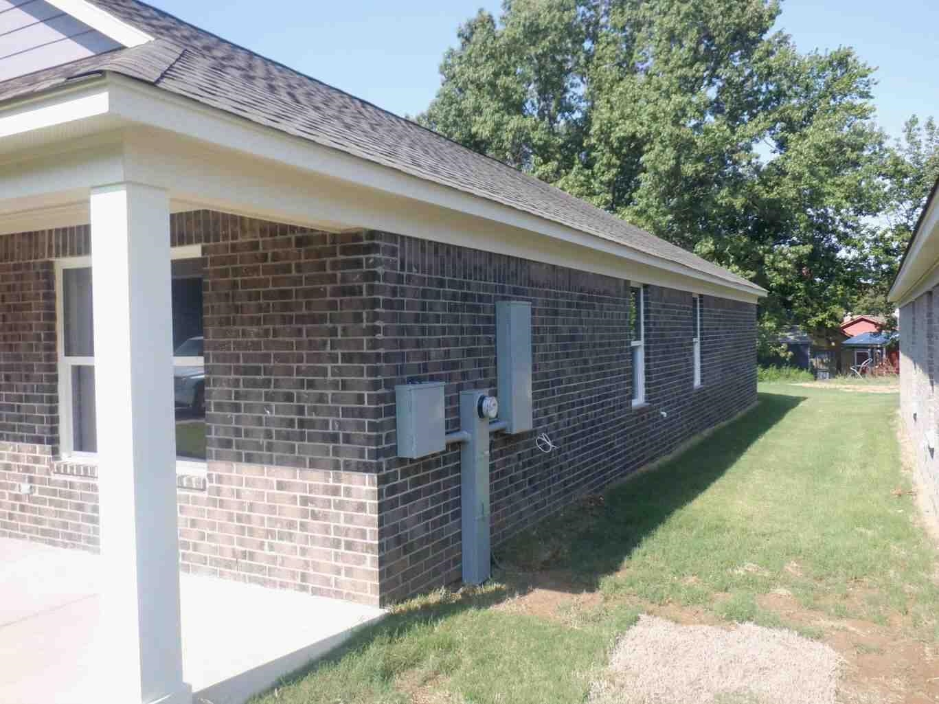 5253 Zodiac Road Memphis, TN 38118 - Photo 2 of 3 View of side of home featuring brick siding, a shingled roof, and a lawn