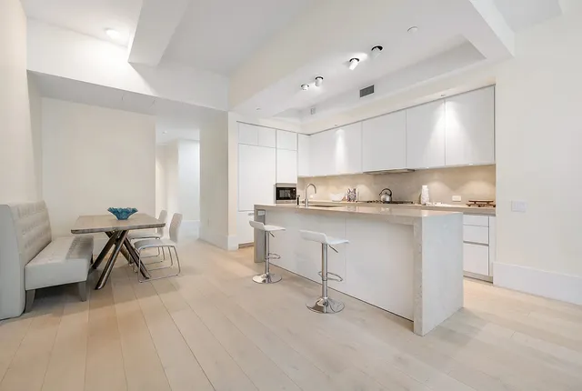 a kitchen with white cabinets and chairs