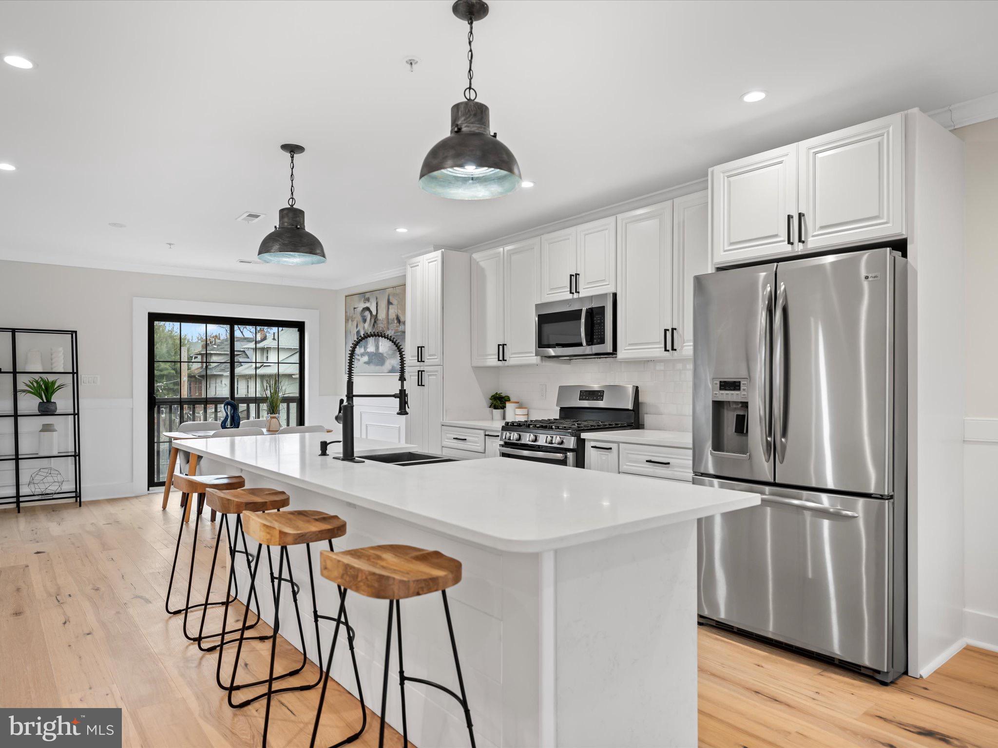 509 Randolph Street Northwest, Unit 2 Washington, DC 20011 - Photo 11 of 23 a kitchen with stainless steel appliances granite countertop a refrigerator a sink a stove a dining table and chairs with wooden floor
