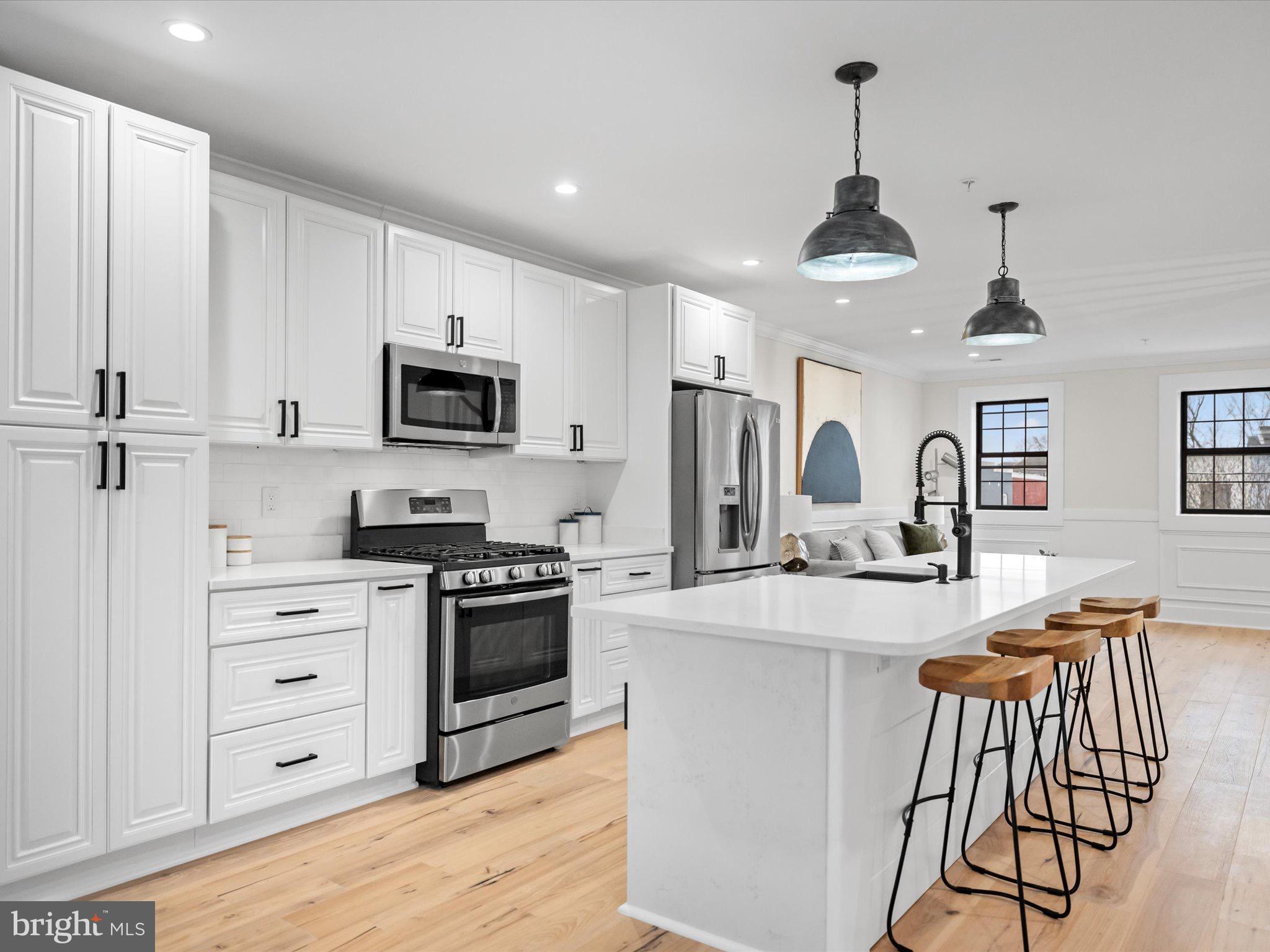 509 Randolph Street Northwest, Unit 2 Washington, DC 20011 - Photo 2 of 23 a kitchen with stainless steel appliances kitchen island granite countertop a stove a sink a refrigerator and white cabinets with wooden floor
