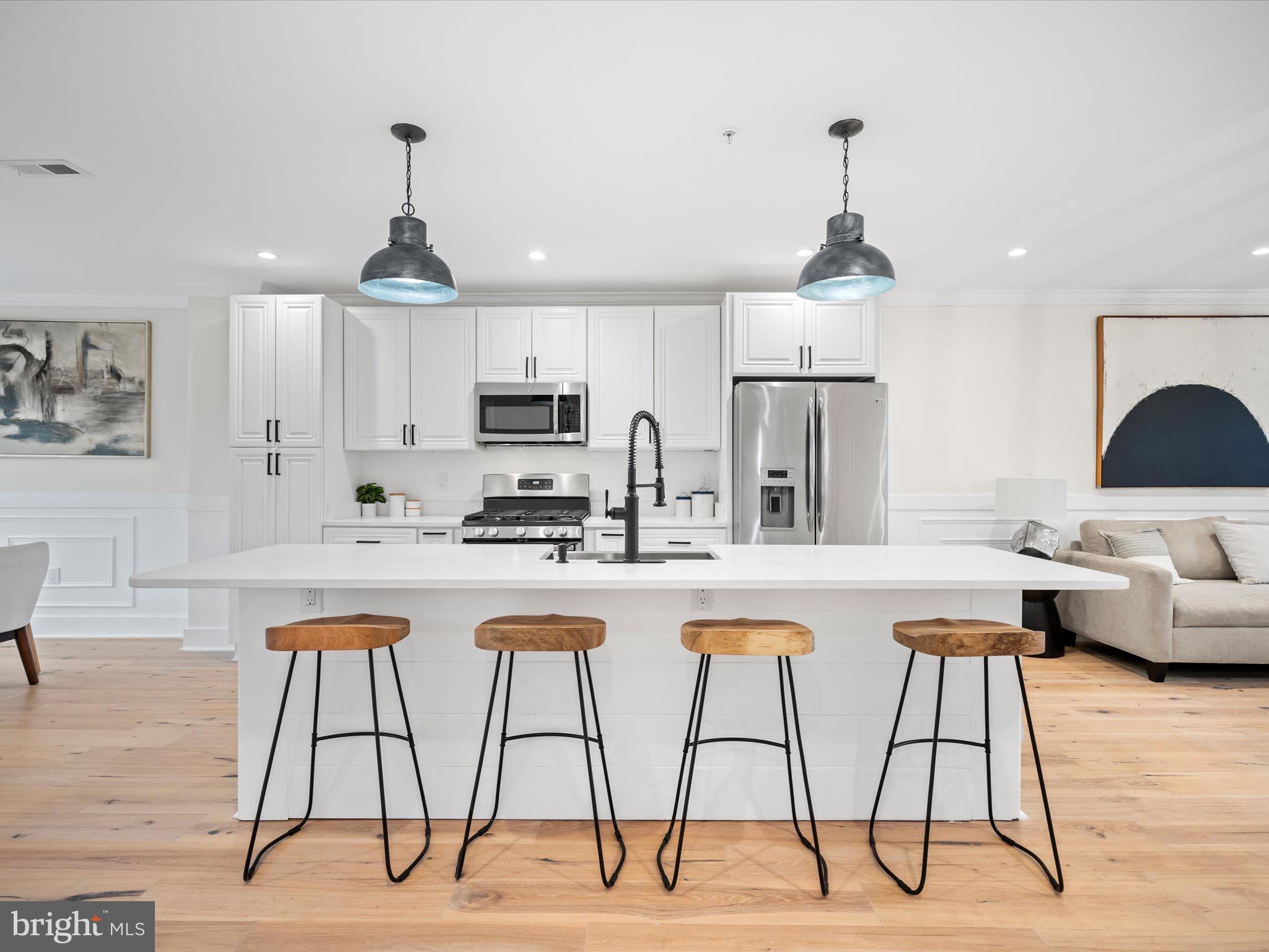 509 Randolph Street Northwest, Unit 2 Washington, DC 20011 - Photo 10 of 23 a kitchen with stainless steel appliances kitchen island granite countertop a dining table chairs and white cabinets
