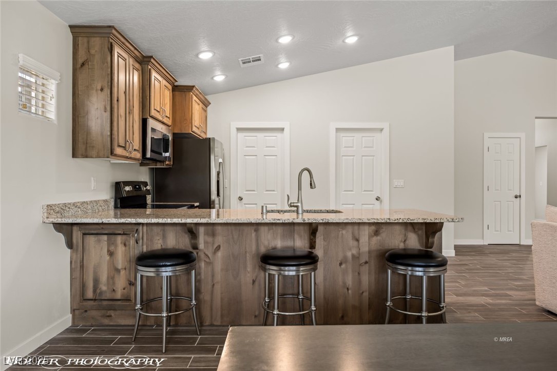 942 Shadow Hawk Ridge Mesquite, NV 89027 - Photo 27 of 67 Kitchen with a sink, stainless steel appliances, lofted ceiling, wood tiled floors, and baseboards
