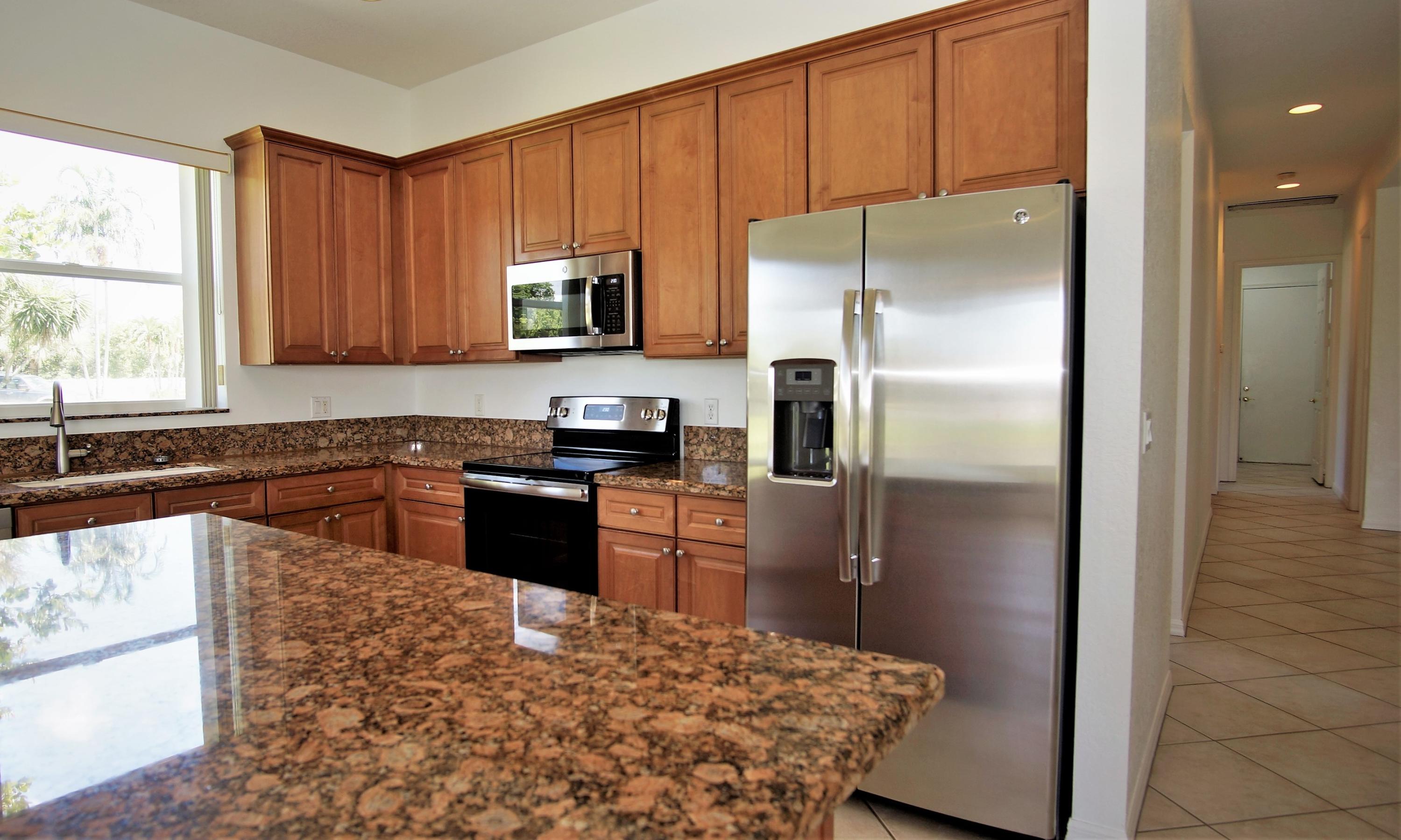 4688 Manderly Drive Wellington, FL 33449 - Photo 11 of 55 a kitchen with granite countertop a refrigerator and a stove top oven