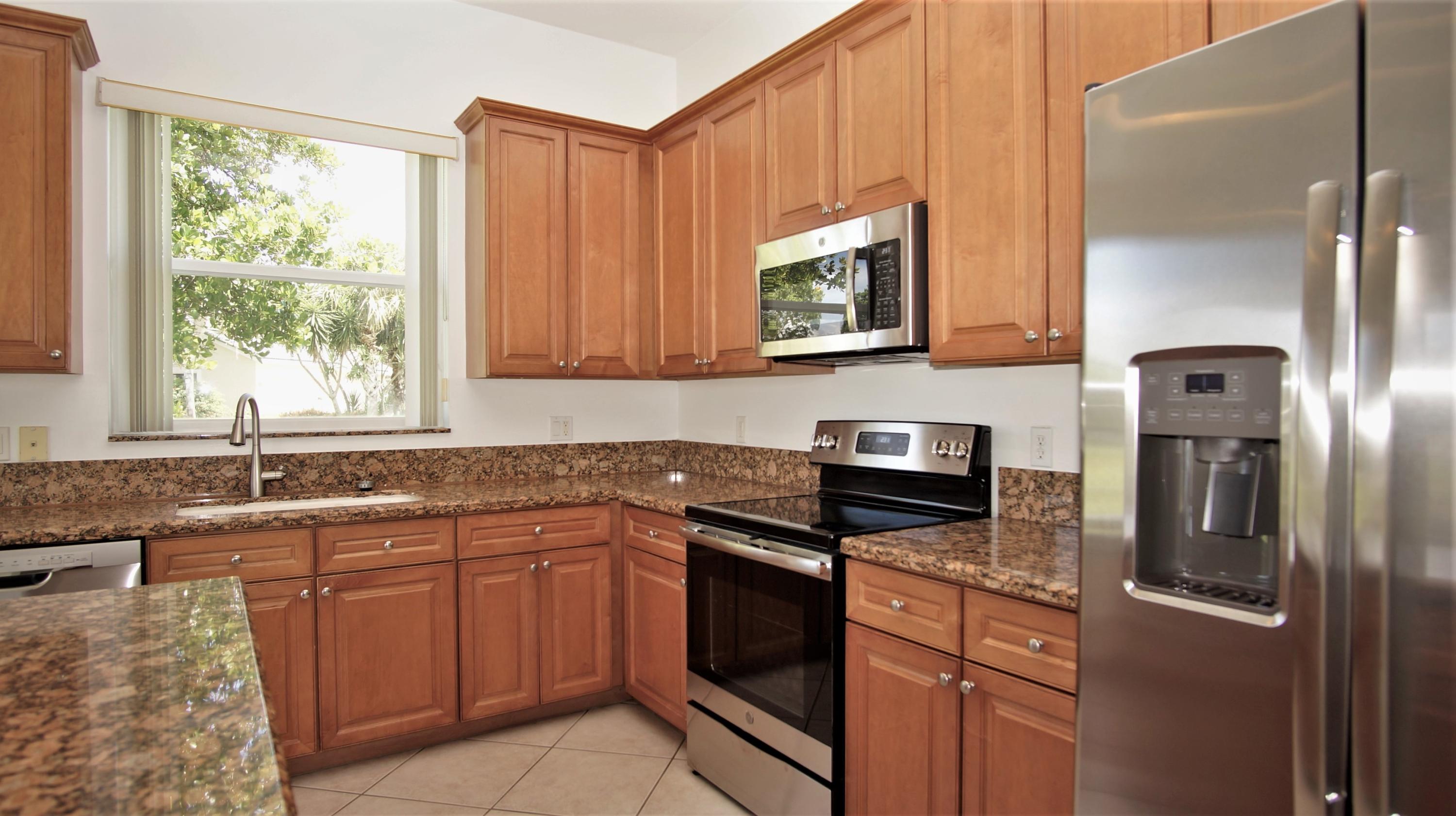 4688 Manderly Drive Wellington, FL 33449 - Photo 12 of 55 a kitchen with stainless steel appliances granite countertop white cabinets a stove a sink and a microwave