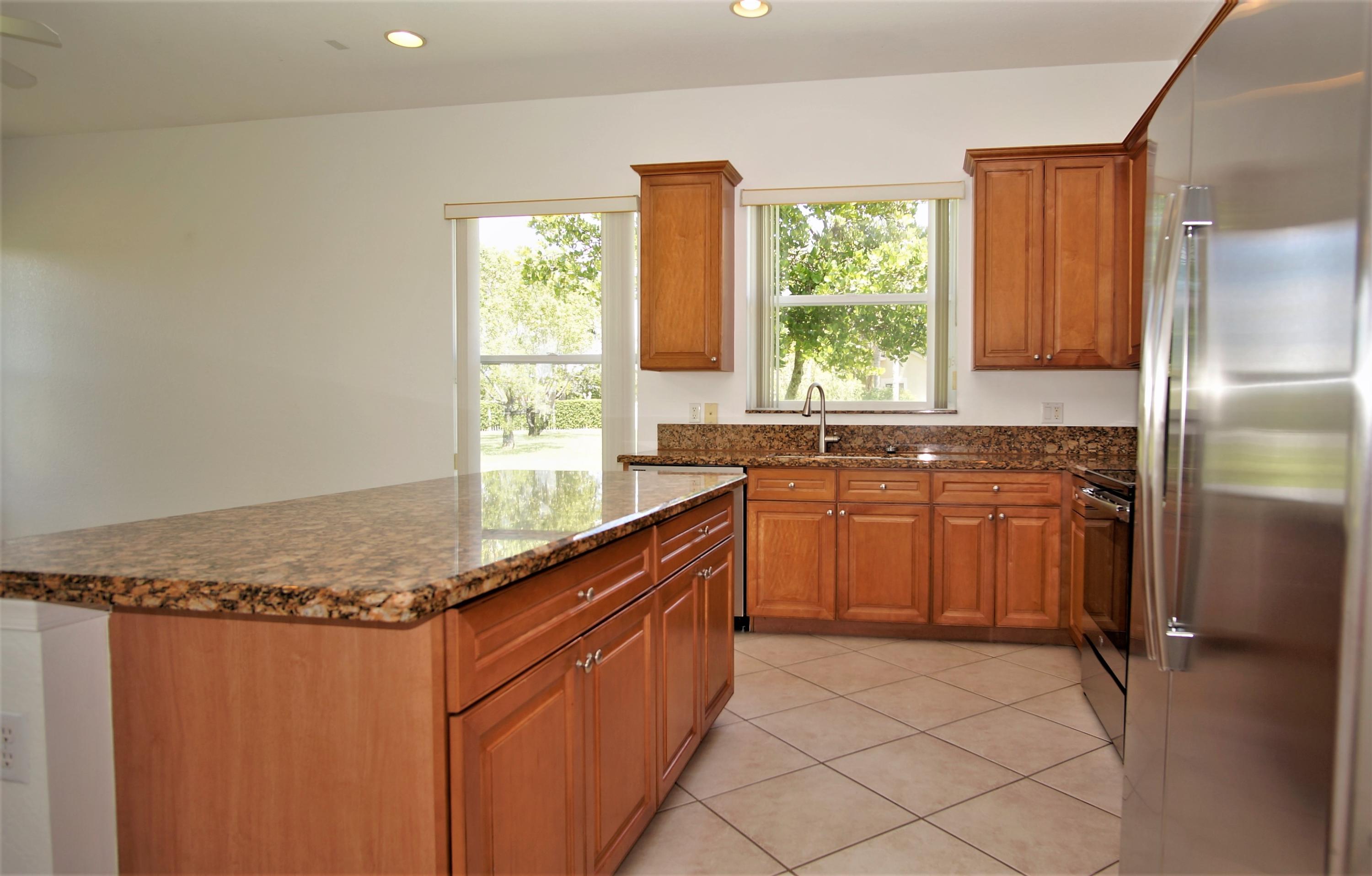 4688 Manderly Drive Wellington, FL 33449 - Photo 13 of 55 a kitchen with granite countertop a sink window and cabinets